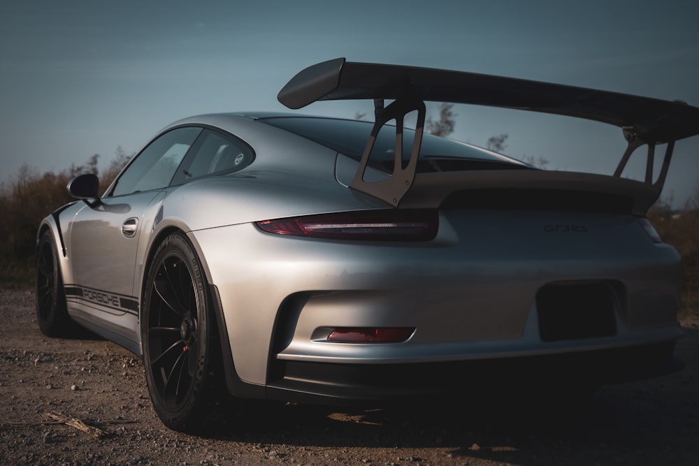 a silver sports car parked on a dirt road