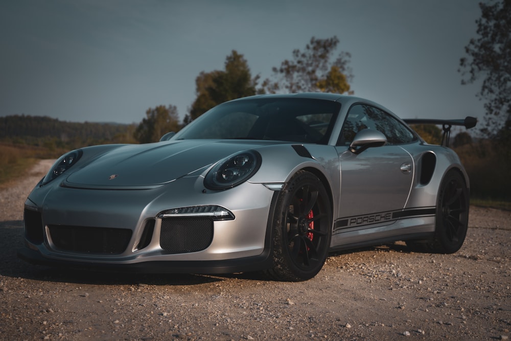 a silver sports car parked on a gravel road