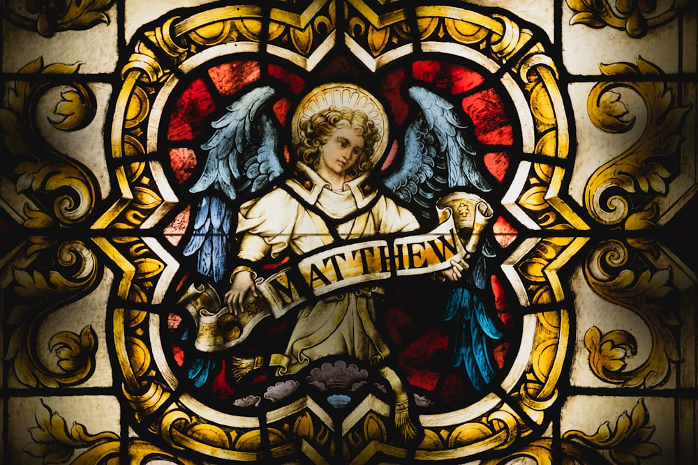 a stained glass window with an angel holding a banner
