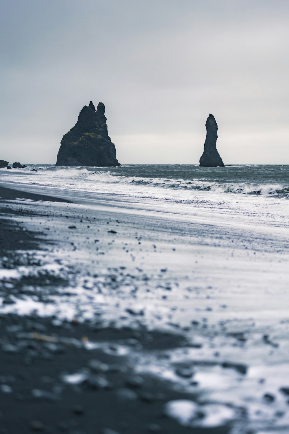 a black sand beach with a rock formation in the distance