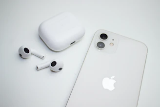 Wireless earbuds displayed alongside a smartphone on a clean desk setup.