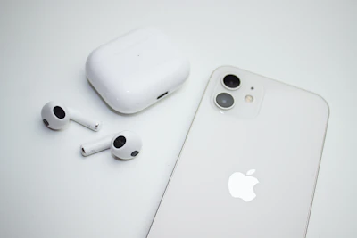 Wireless earbuds displayed alongside a smartphone on a clean desk setup.