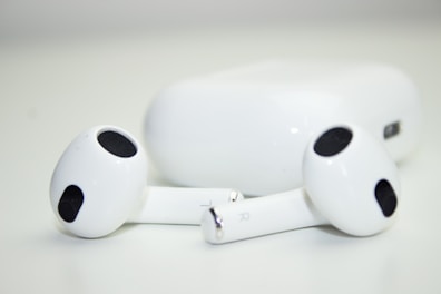 Wireless earbuds charging in their compact case on a smooth surface.