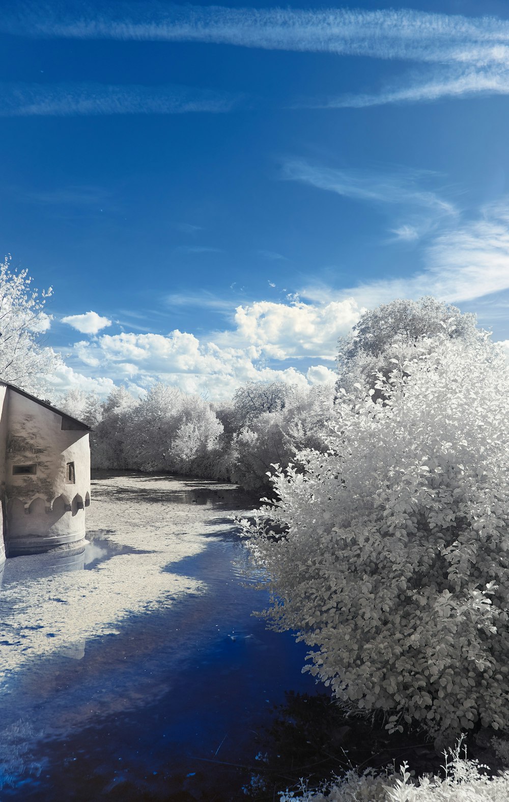 a house sitting next to a river under a blue sky