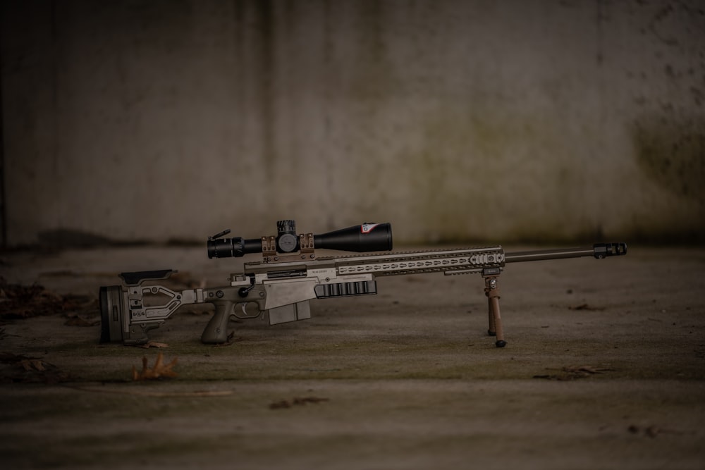 a rifle laying on the ground with a scope