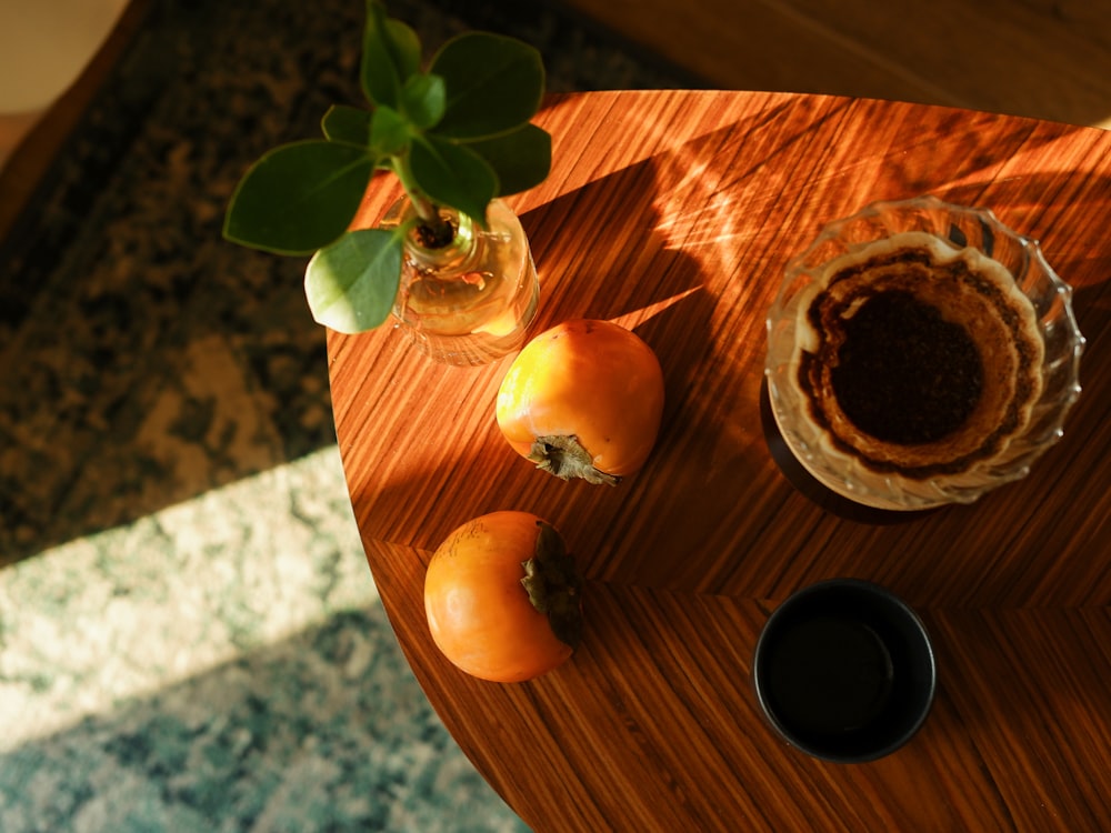 a wooden table topped with a vase filled with oranges