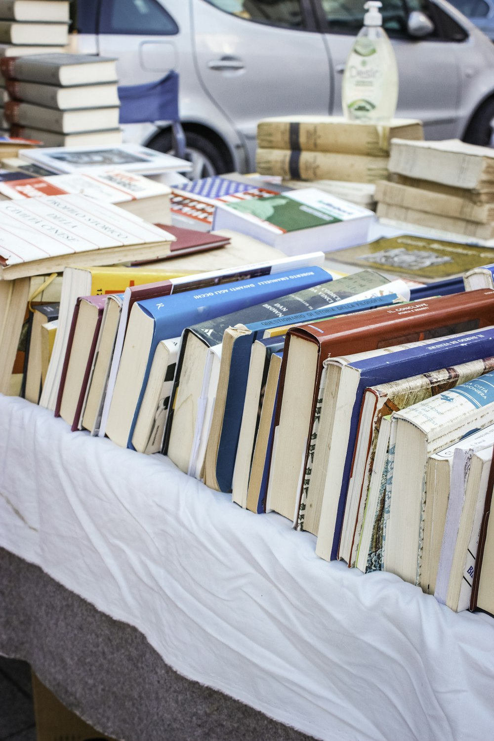 a table topped with lots of books next to a car