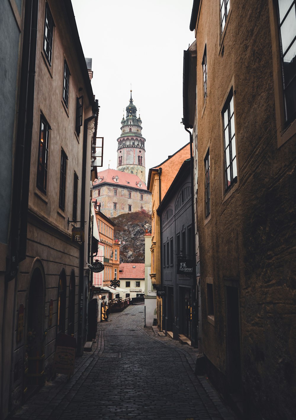 a narrow street with buildings and a clock tower in the background