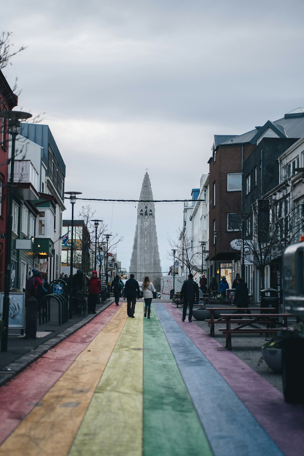 a rainbow painted street with people walking down it