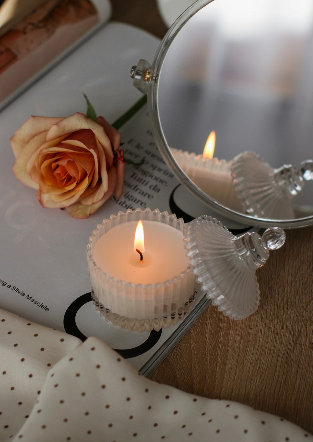 uma rosa sentada em cima de uma mesa ao lado de um espelho