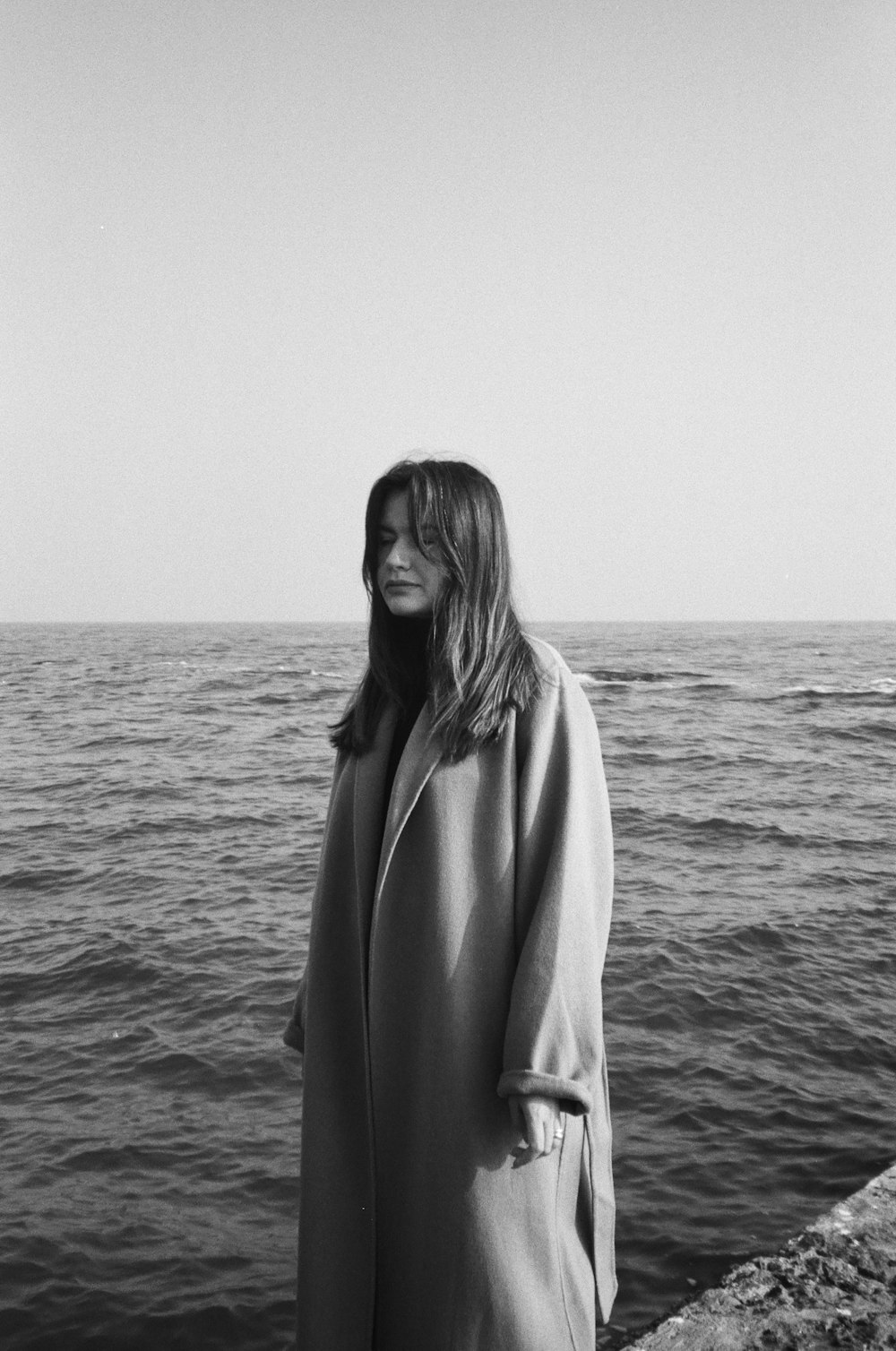 a black and white photo of a woman in a trench coat