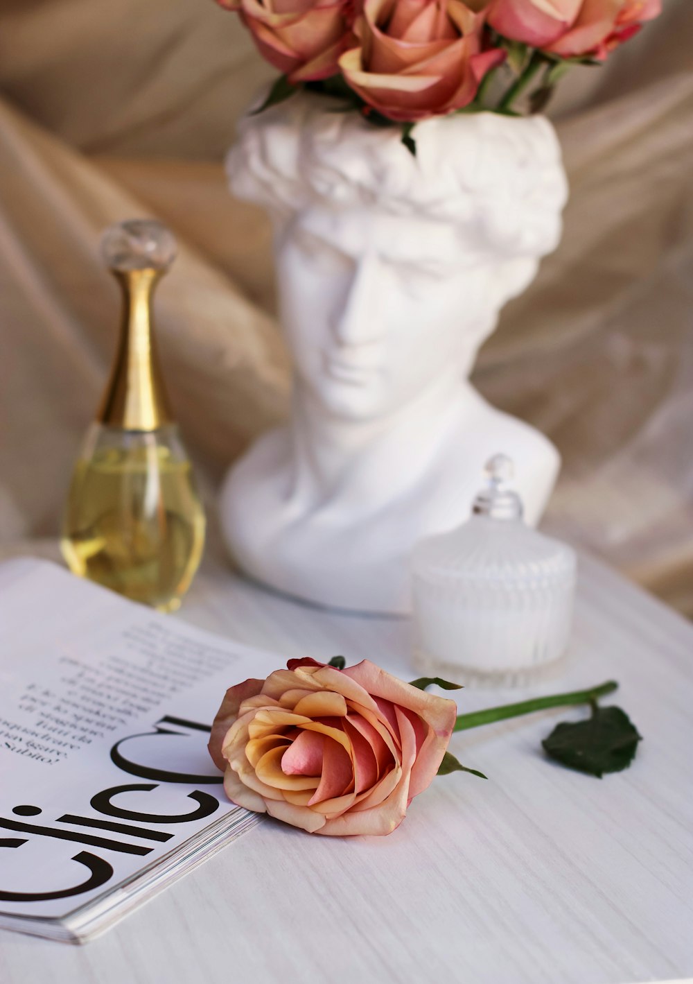 a rose sitting on top of a table next to a bottle of perfume