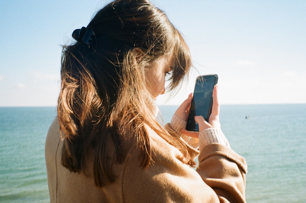 a woman looking at her cell phone on the beach