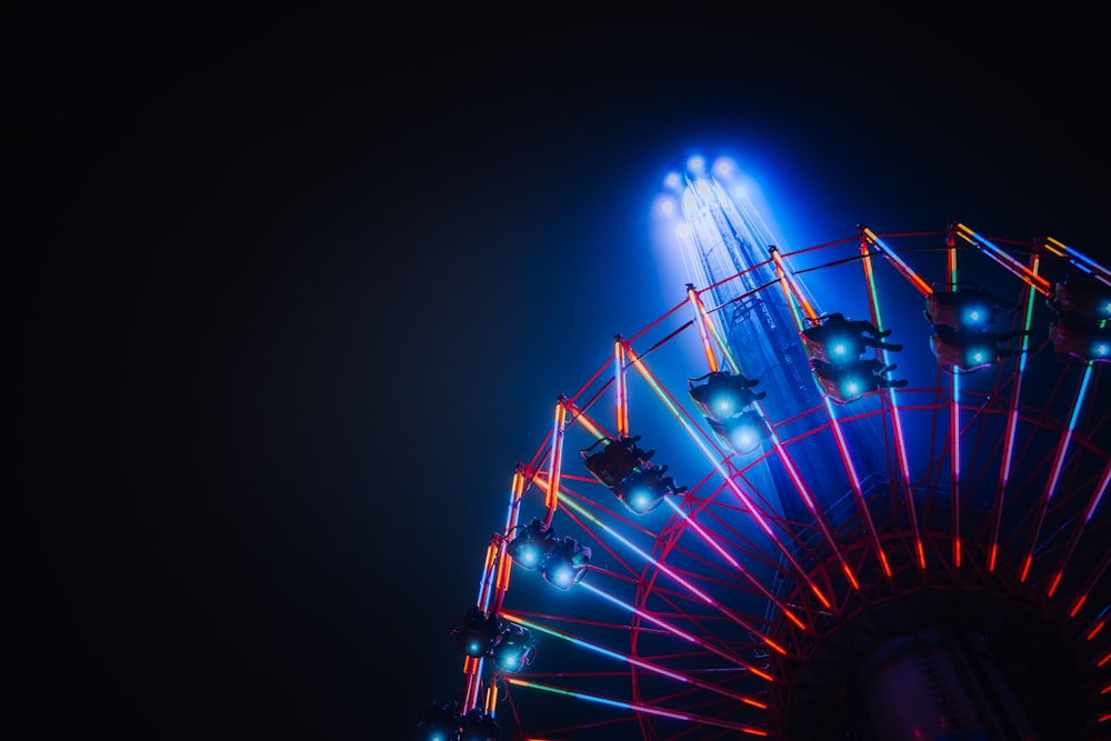 a ferris wheel lit up at night with bright lights