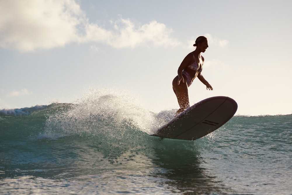 a woman riding a surfboard on a wave in the ocean