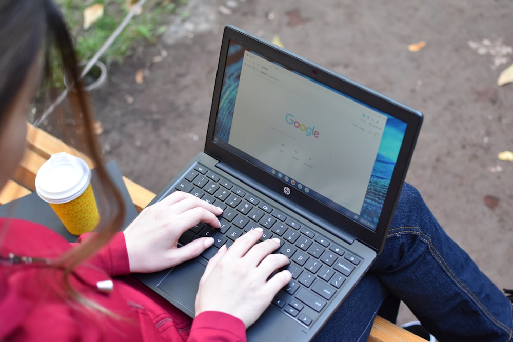 a woman sitting on a bench using a laptop computer