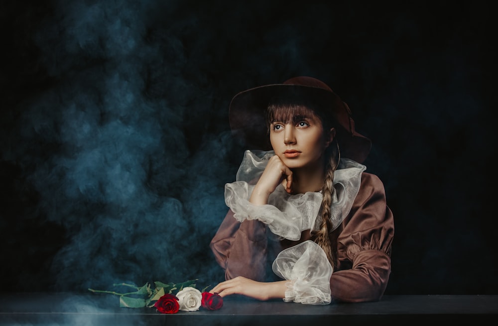 a woman sitting at a table with a rose in her hand