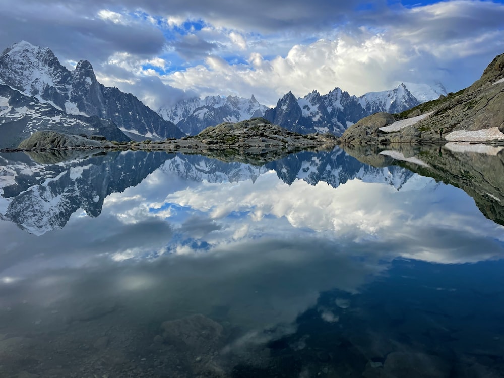 a mountain range is reflected in the still water of a lake