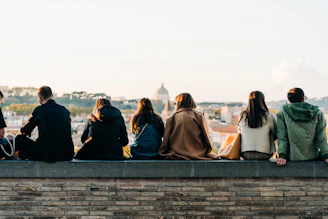 a group of people sitting on top of a brick wall