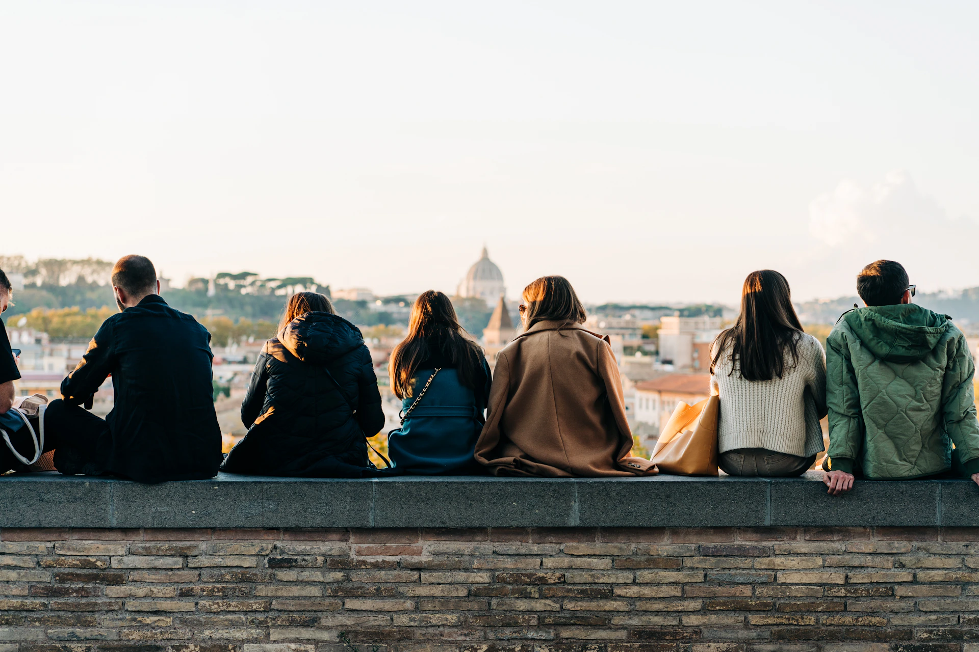 a group of people sitting on top of a brick wall