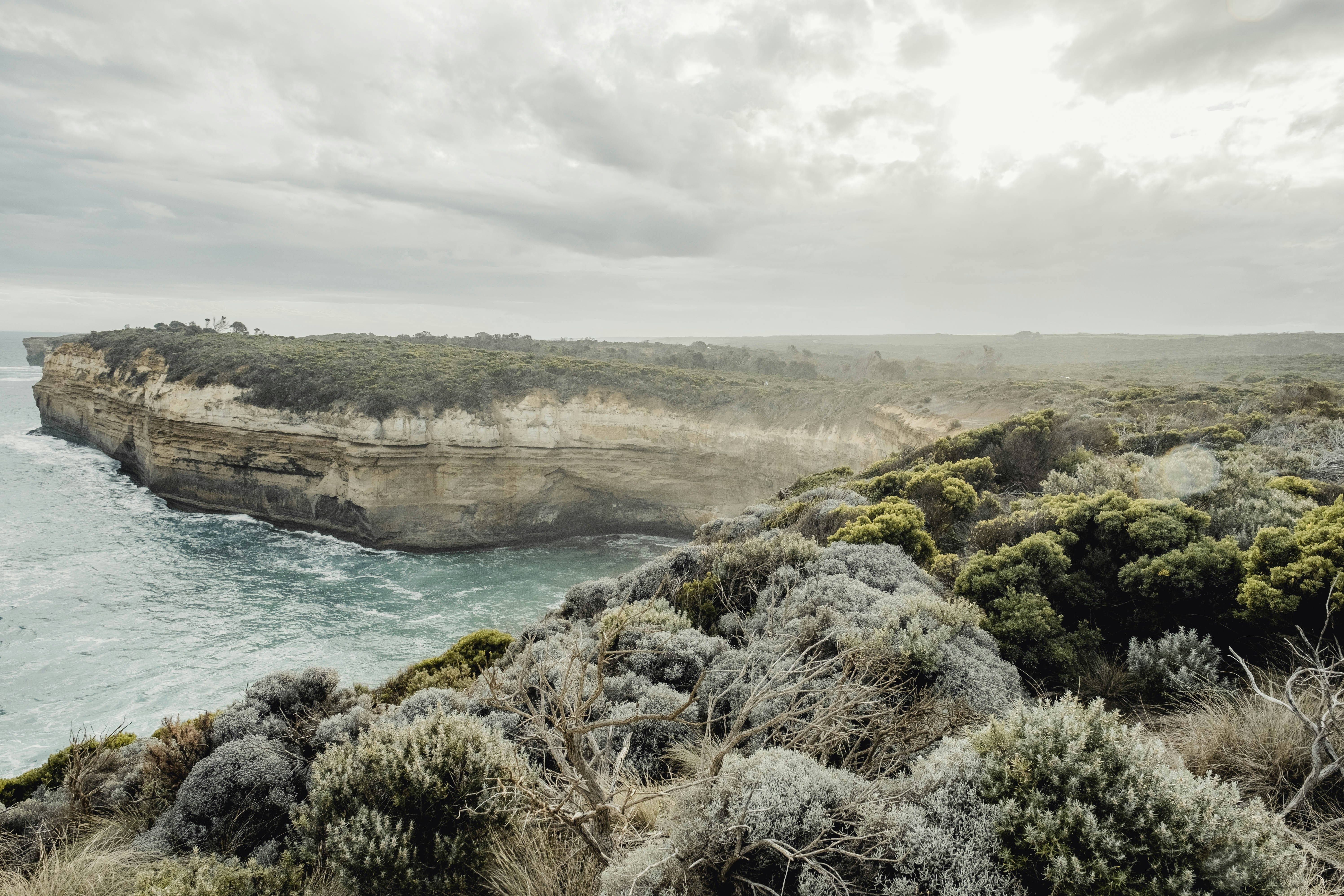 a rocky cliff overlooks the ocean on a cloudy day