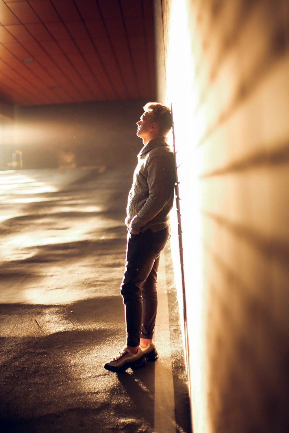 a woman leaning against a wall in a parking lot
