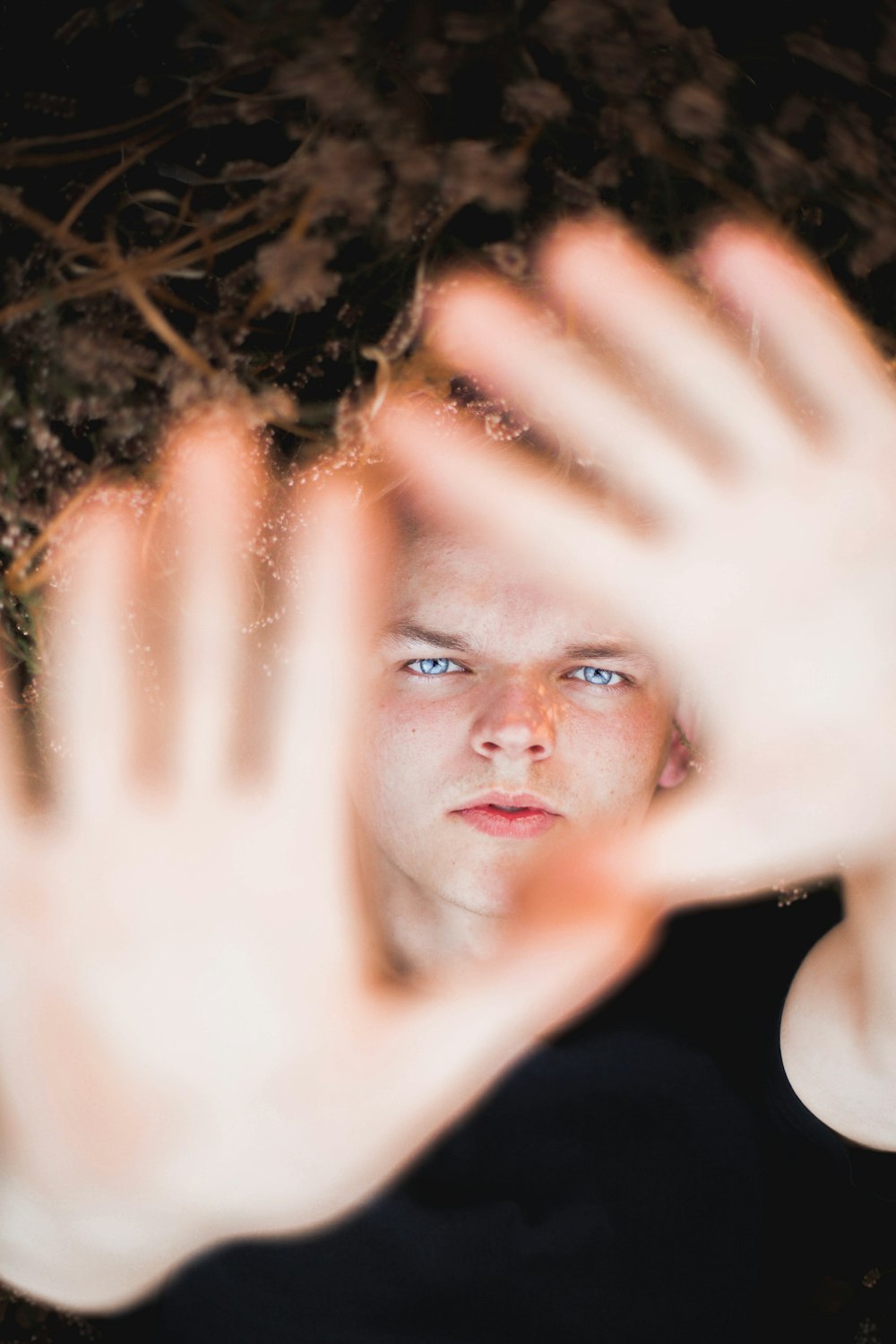 a young man holding his hands up in front of his face