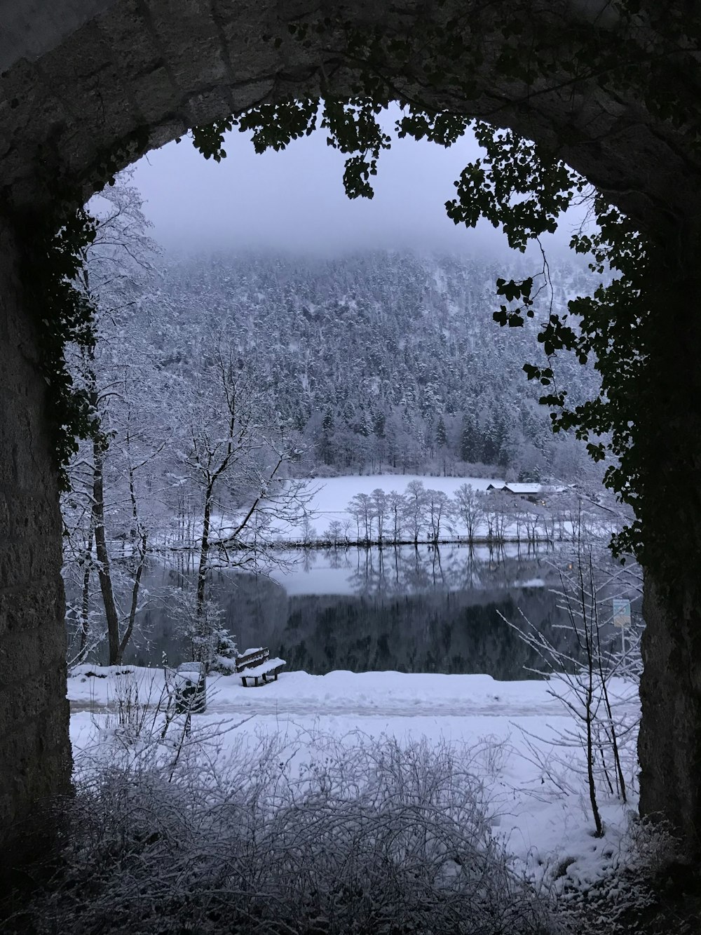 a view of a lake through a stone arch