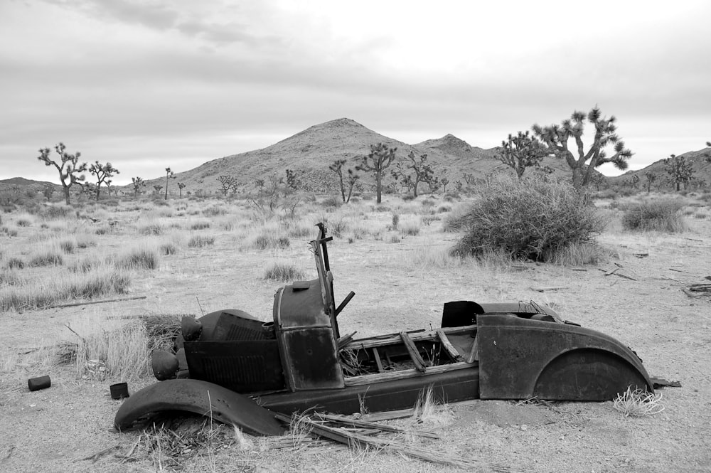 an old car sitting in the middle of a desert