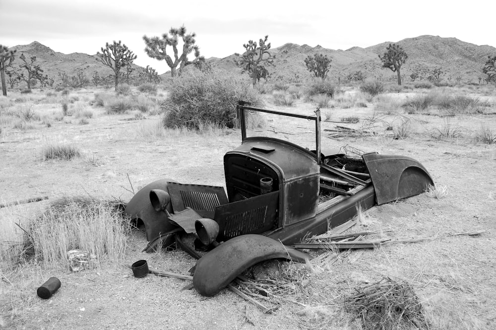 a black and white photo of an old car in the desert