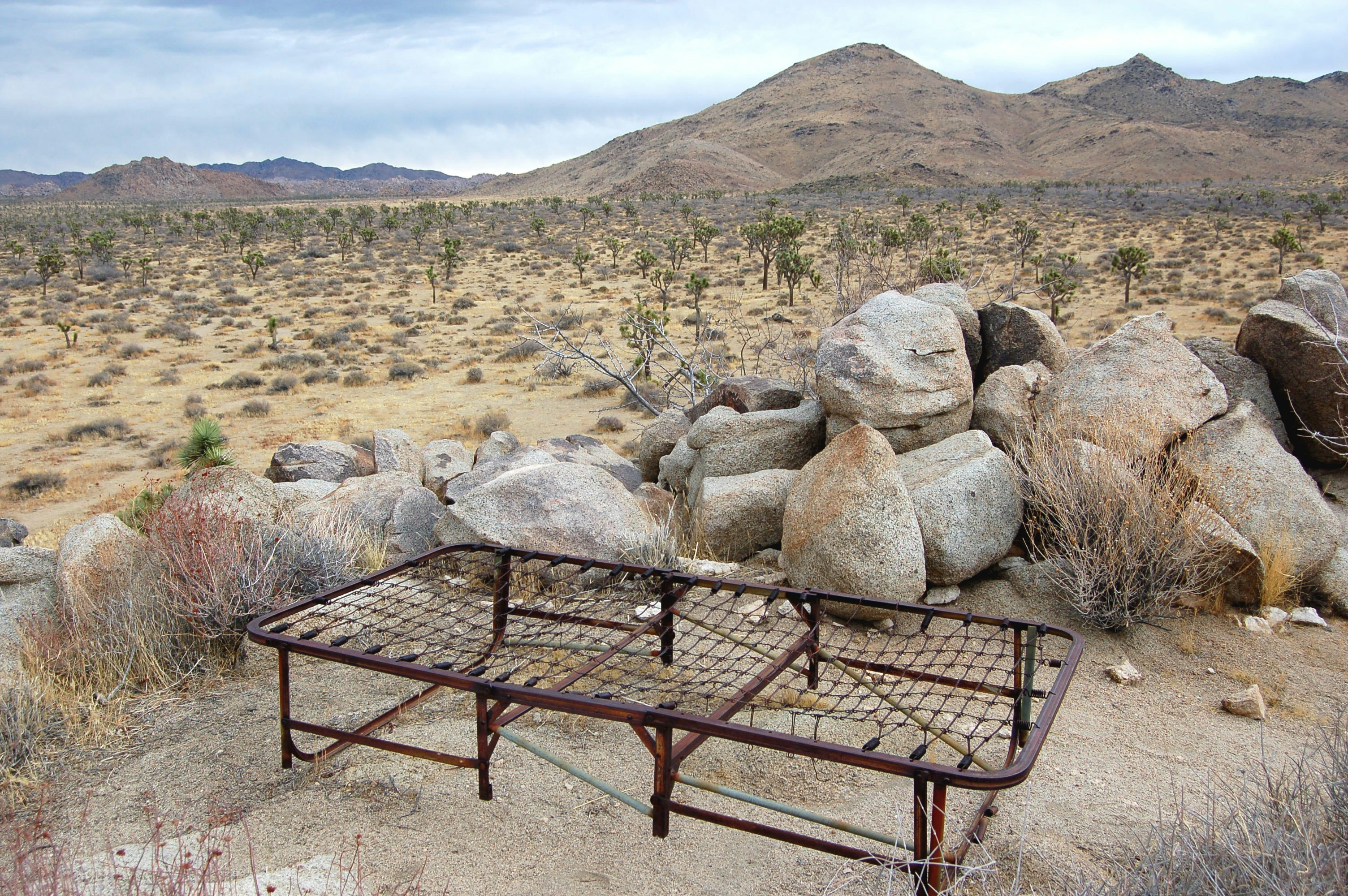 a metal bed frame sitting in the middle of a desert