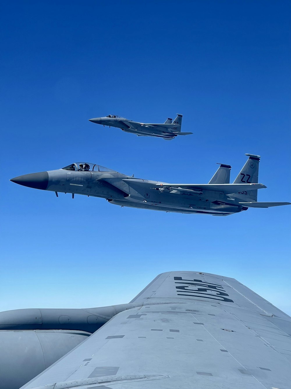 two fighter jets flying next to each other in the sky