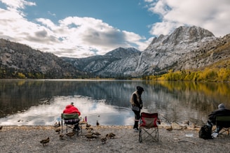 a couple of people sitting in chairs near a lake