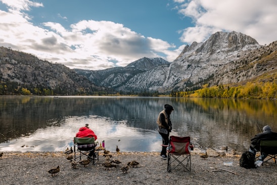 a couple of people sitting in chairs near a lake
