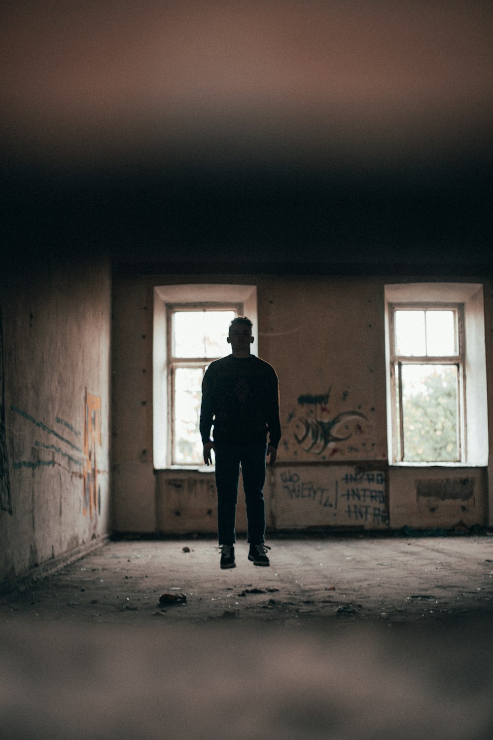 a man standing in an empty room with graffiti on the walls