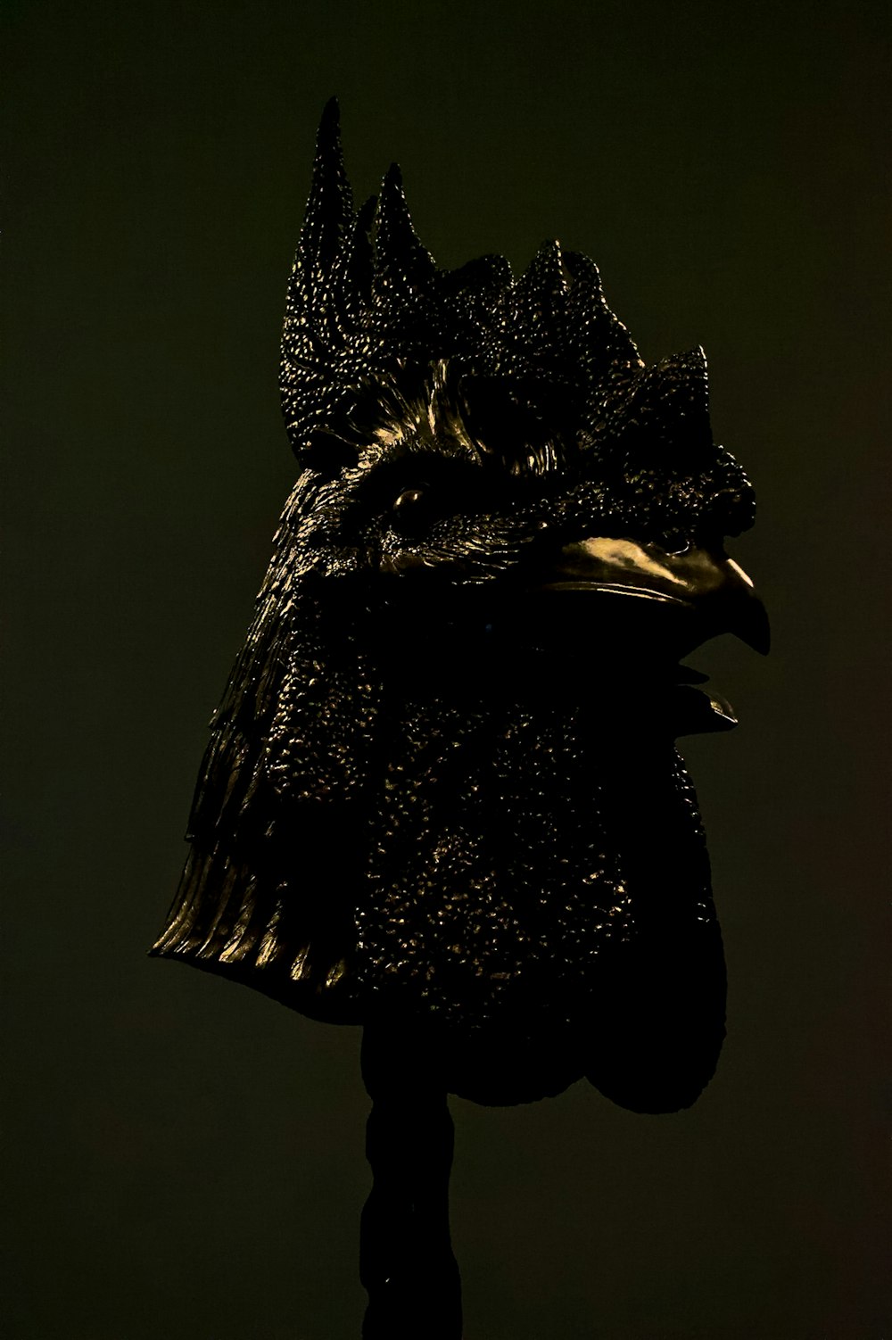 a statue of a bird with a black background