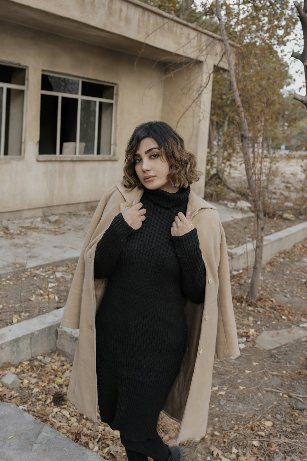 a woman in a black dress and a tan coat