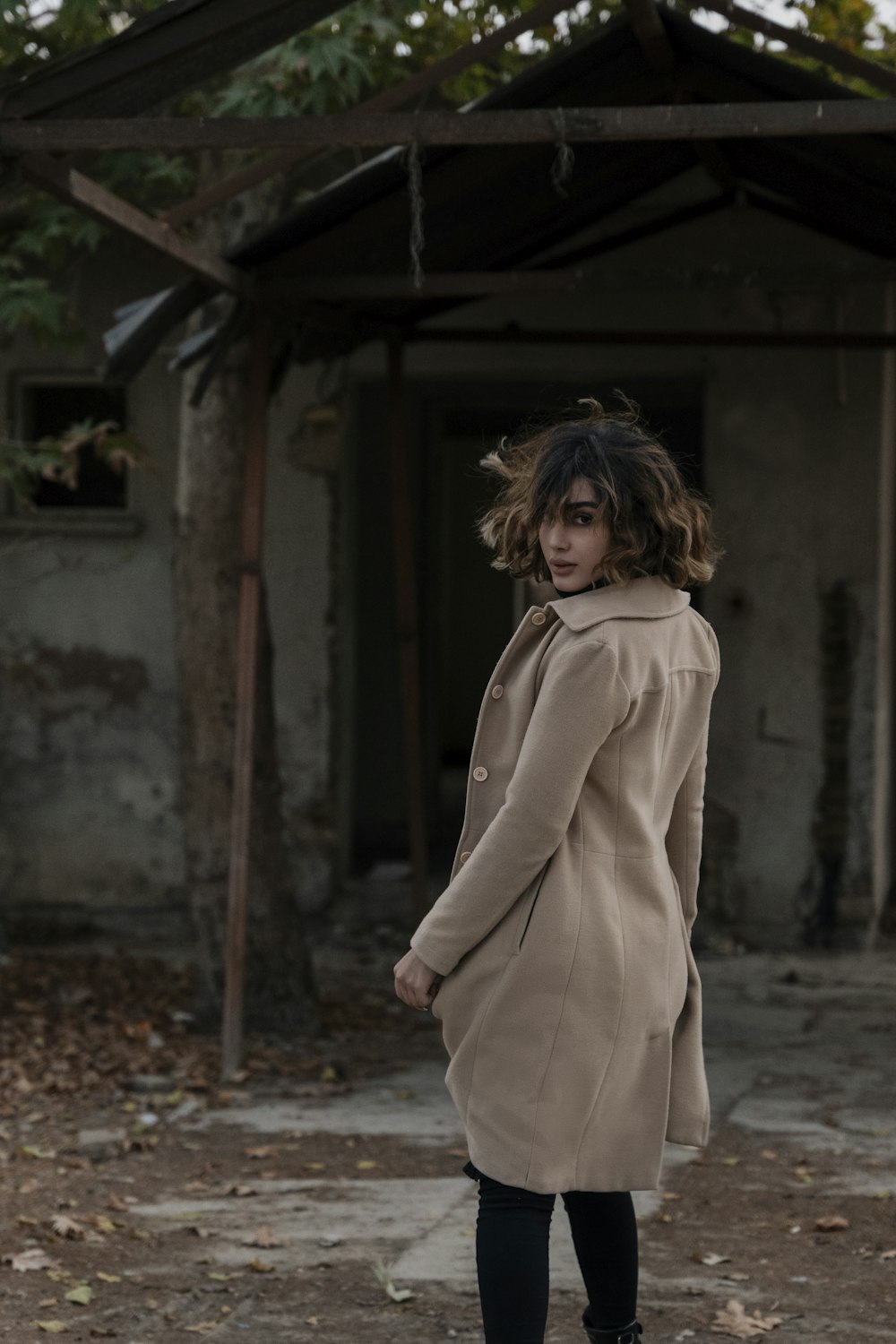 a woman in a trench coat standing in front of a building
