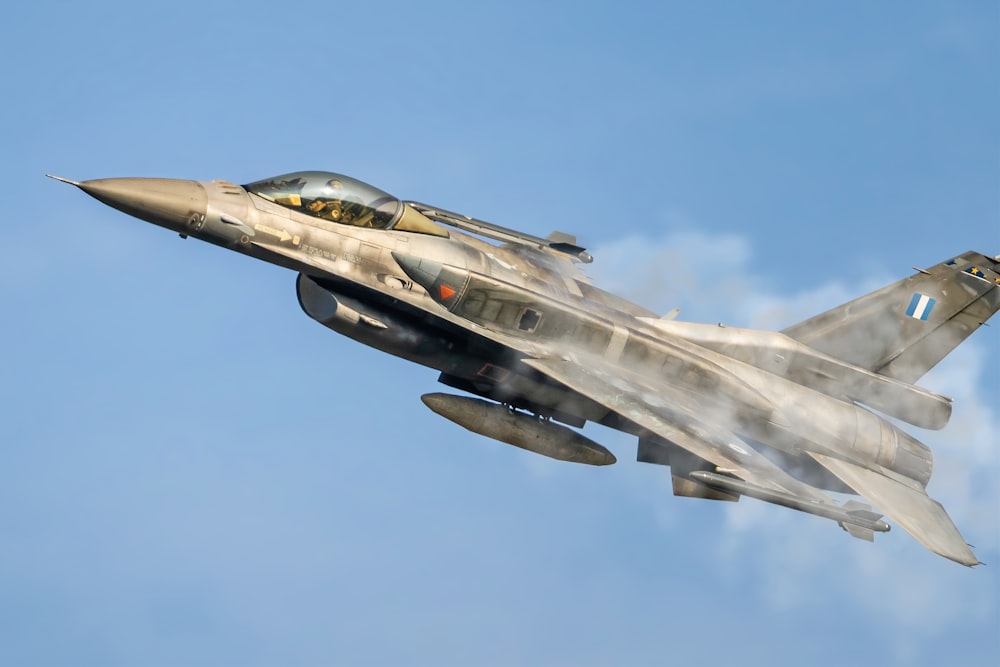 a fighter jet flying through a blue sky