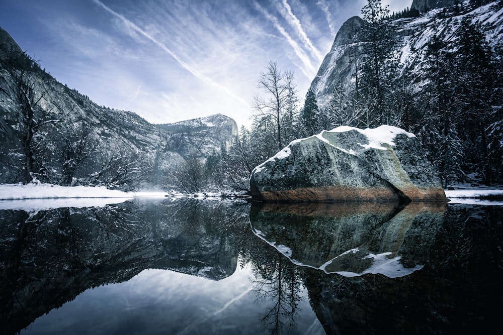 a lake surrounded by snow covered mountains under a blue sky