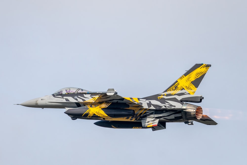 a fighter jet flying through a blue sky