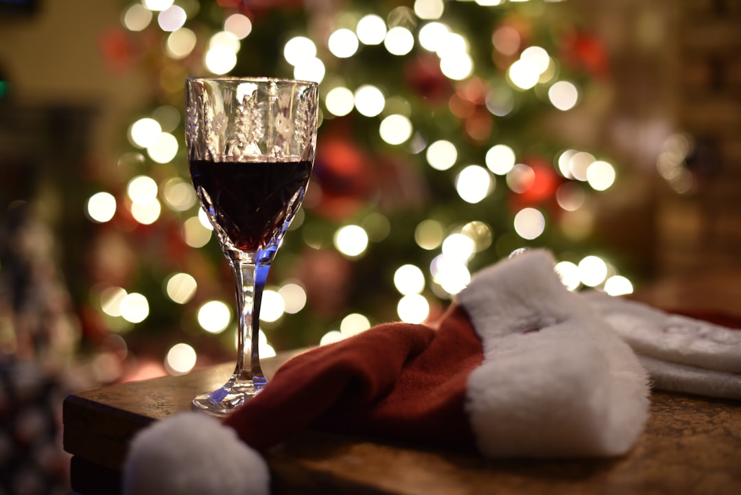 a glass of wine and a santa hat on a table, Where