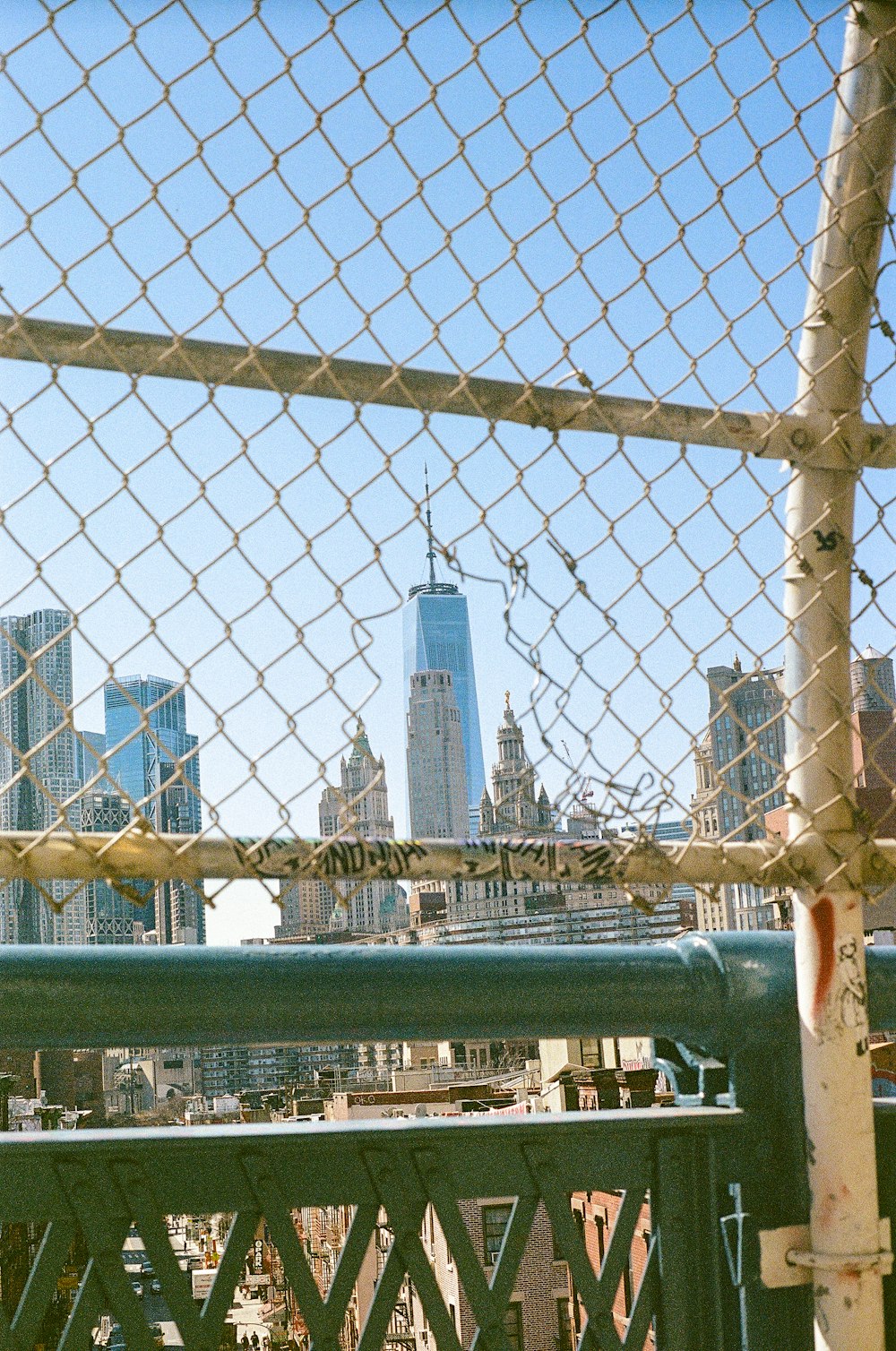 a view of a city through a chain link fence