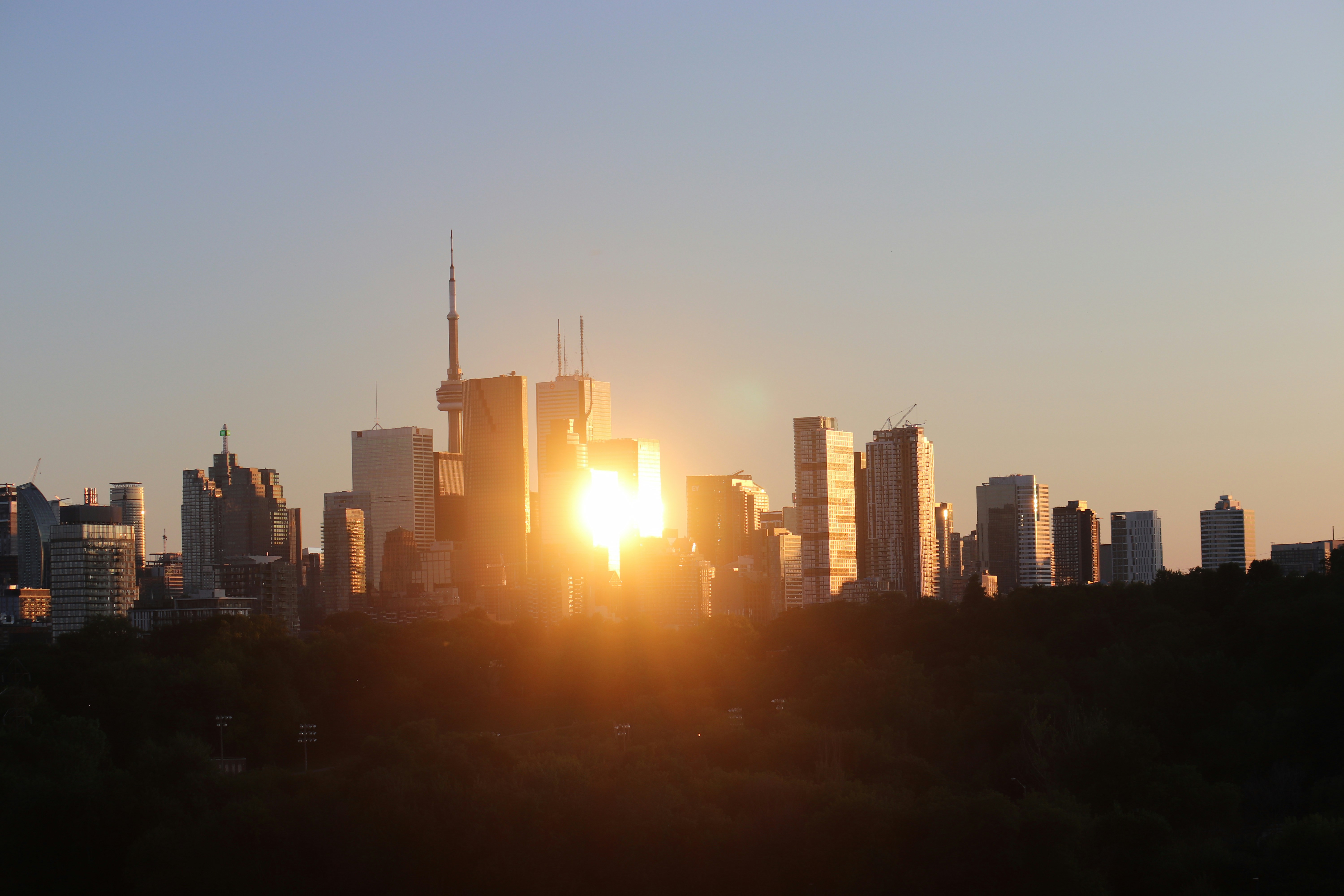 the sun is setting over a city with tall buildings