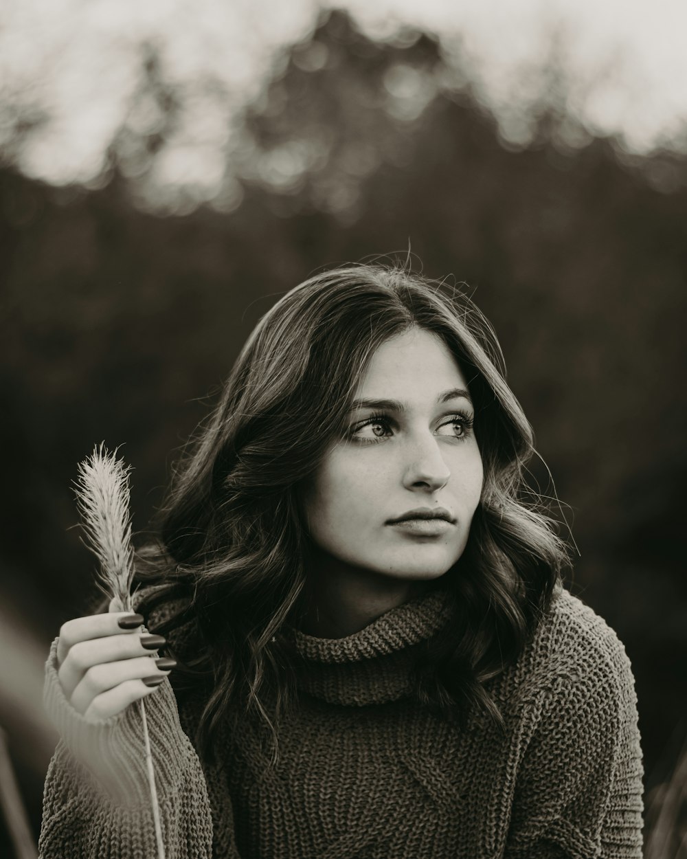 a black and white photo of a woman holding a flower