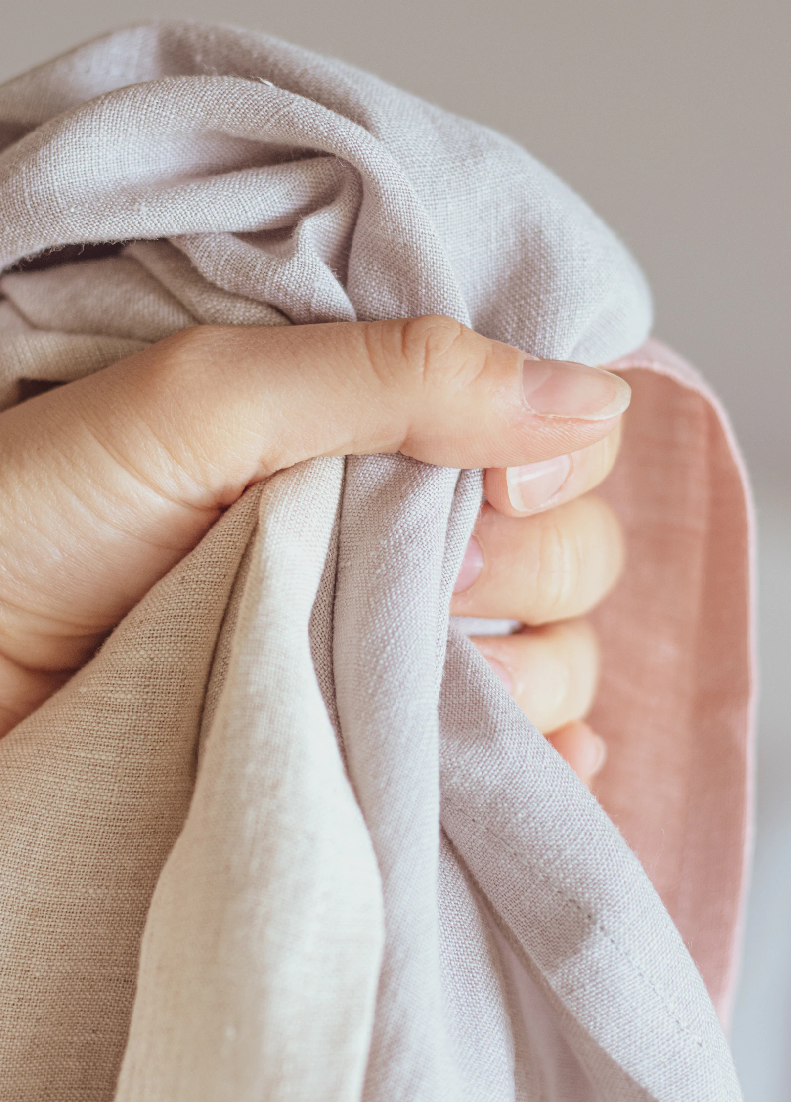 Main effleurant un tissu de lin naturel aux teintes douces