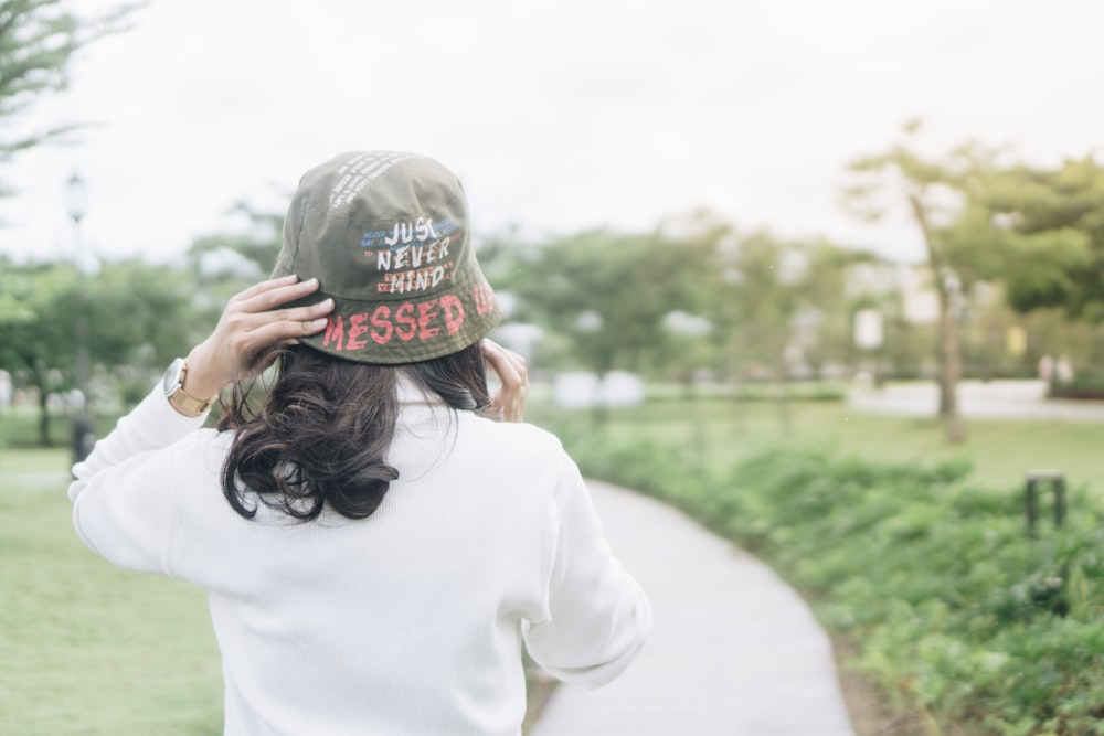 a woman with a hat on her head walking down a path