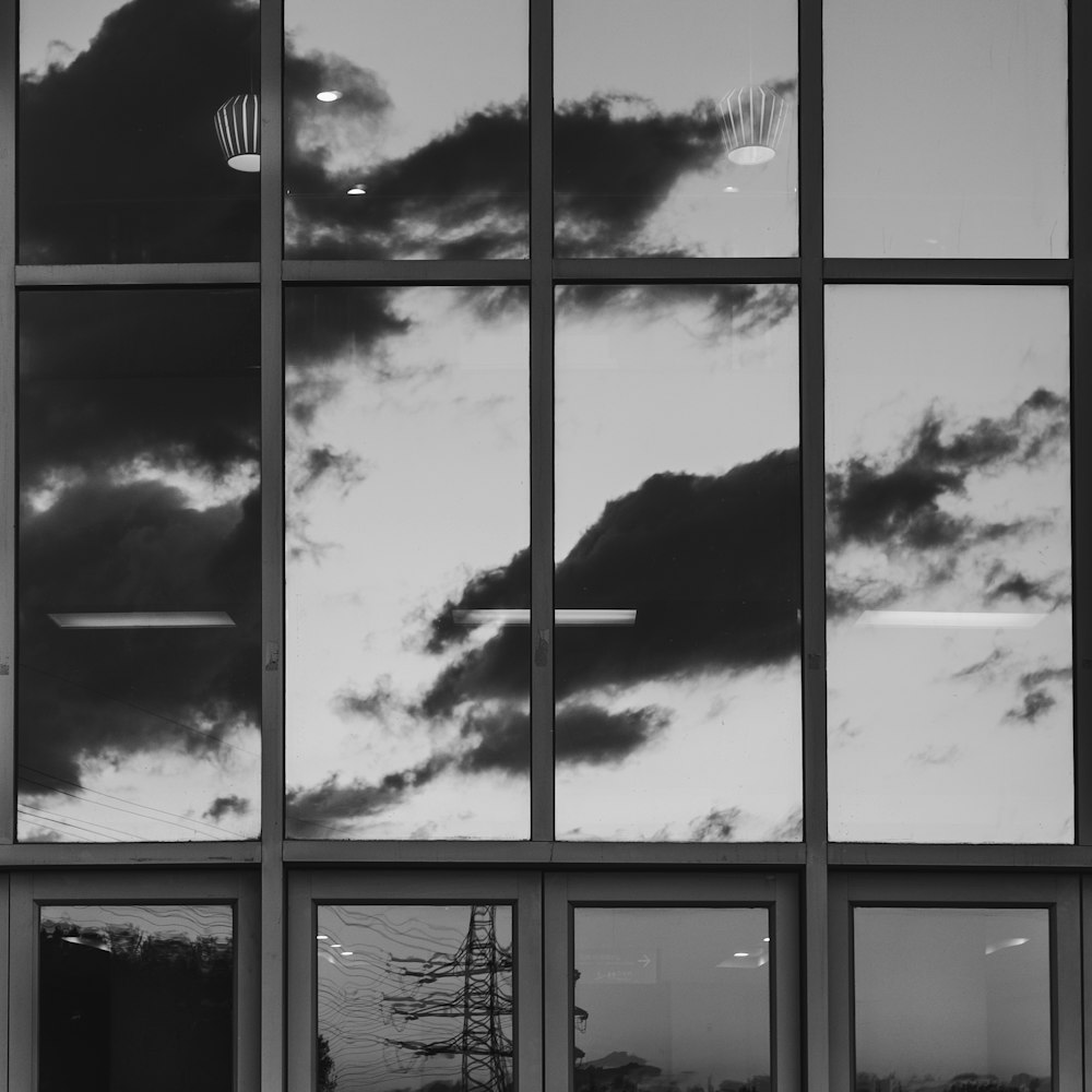 a black and white photo of clouds reflected in a window