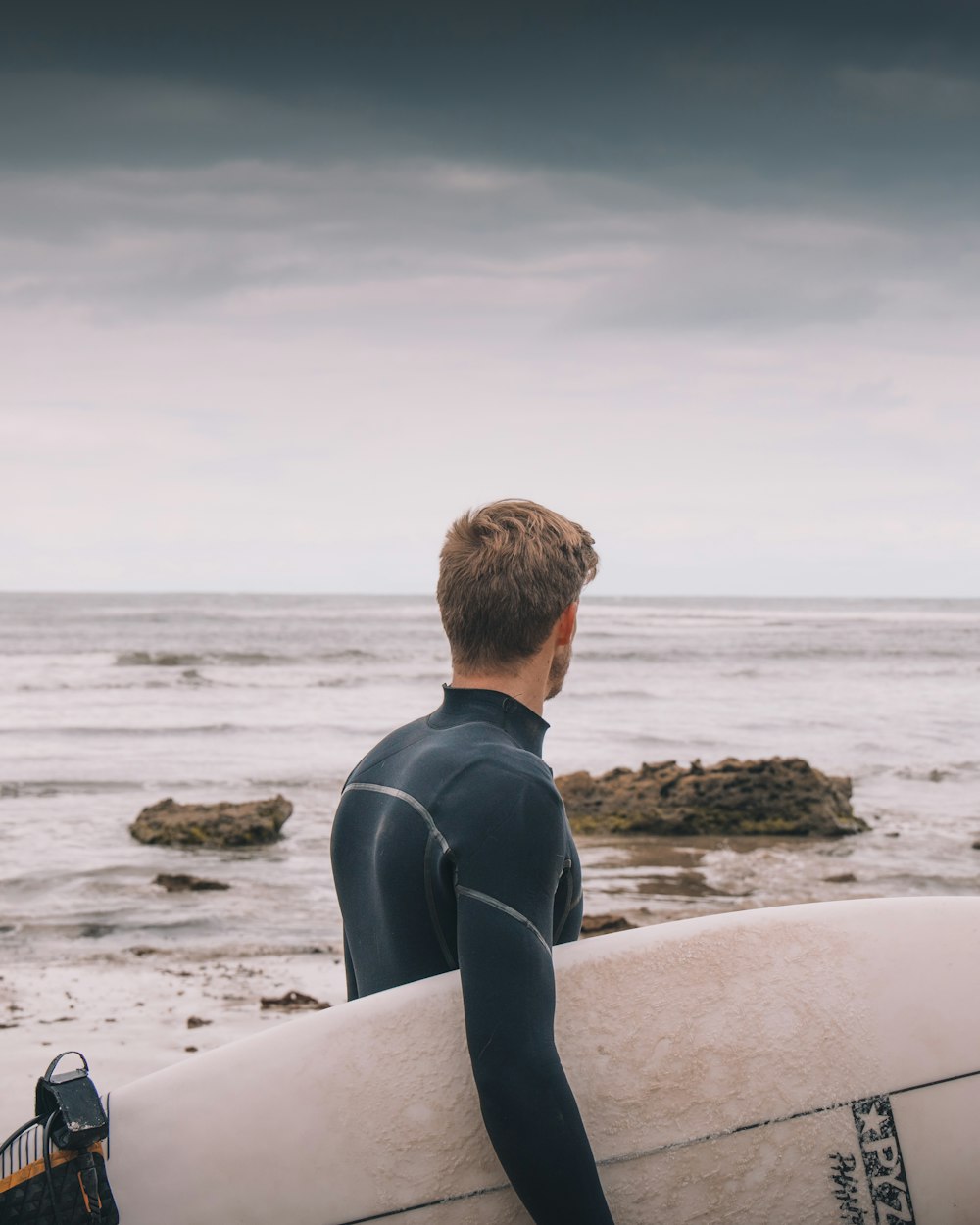 a man in a wet suit holding a surfboard