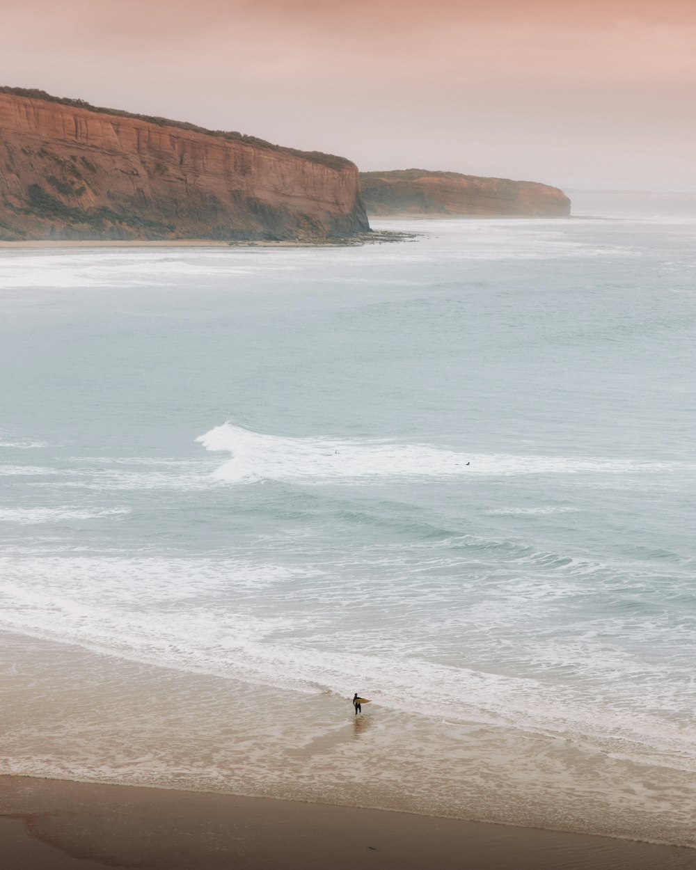 Una persona caminando en una playa junto al océano